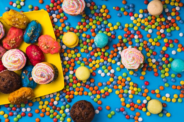 Vista superior pasteles coloridos rodeados por bombones