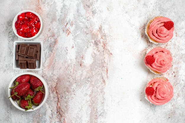 Vista superior de pasteles de fresa rosa con crema sobre superficie blanca