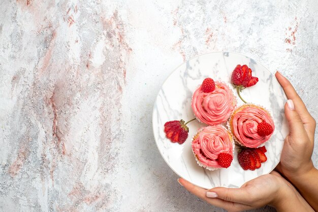 Vista superior de pasteles de fresa rosa con fresas rojas frescas sobre superficie blanca