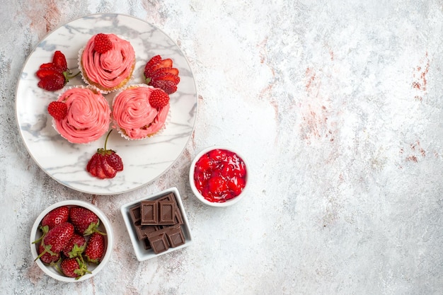 Vista superior de pasteles de fresa rosa con mermelada en superficie blanca