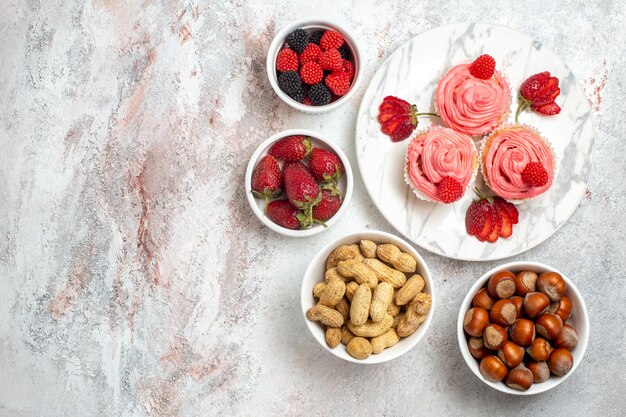 Vista superior de pasteles de fresa rosa con nueces sobre superficie blanca