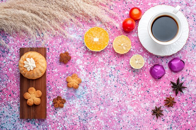 Vista superior del pastelito con taza de té de galleta y rodajas de naranja en la superficie rosa