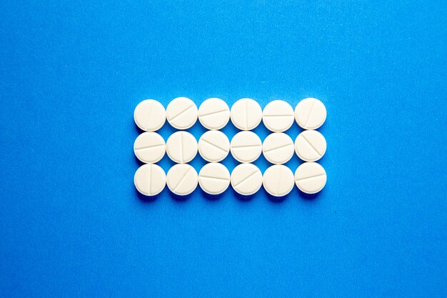 Vista superior de pastillas blancas sobre fondo azul.