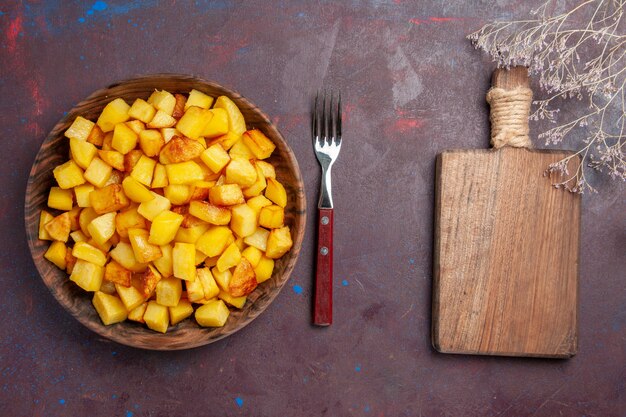 Vista superior de patatas cocidas en rodajas dentro de la placa en el escritorio oscuro