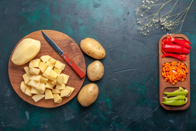 Vista superior de patatas frescas en rodajas con pimientos en rodajas sobre el fondo azul oscuro