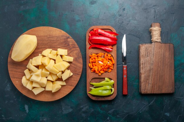 Vista superior de patatas frescas en rodajas con pimientos en rodajas sobre el fondo azul oscuro