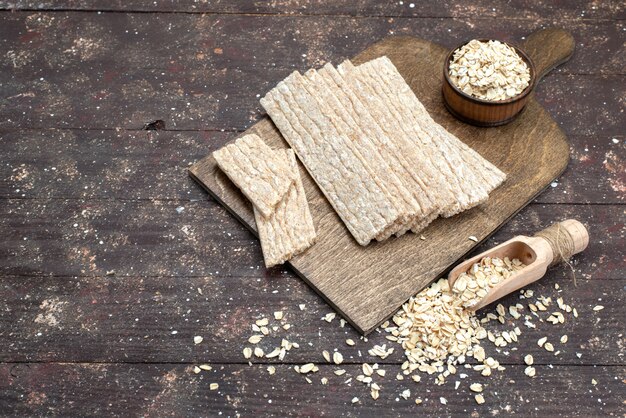 Vista superior patatas fritas y galletas formadas durante mucho tiempo con avena cruda en el escritorio de madera