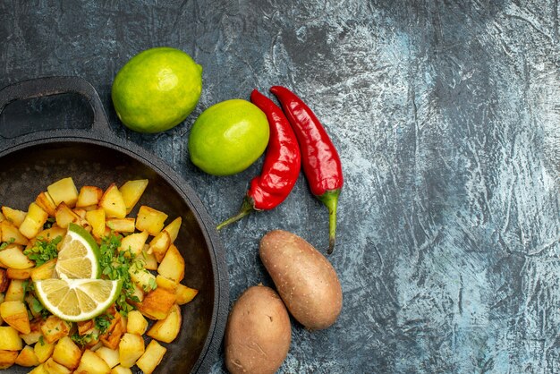 Vista superior de patatas fritas con limón y pimientos sobre fondo gris claro