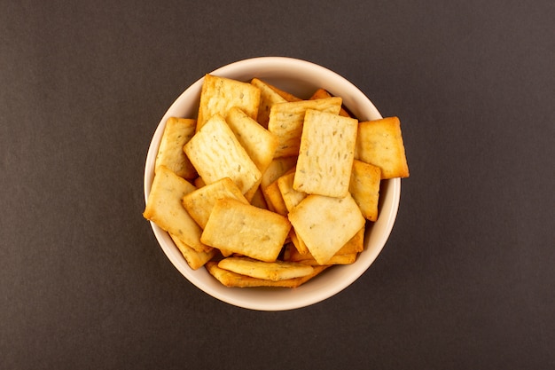 Foto gratuita una vista superior patatas fritas saladas sabrosas galletas de queso dentro de un plato blanco sobre el fondo oscuro bocadillo sal comida crujiente