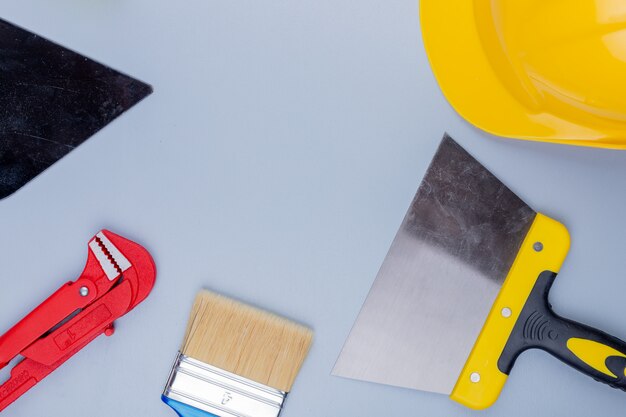 Vista superior del patrón del conjunto de herramientas de construcción como llave de tubo, casco de seguridad, llana, pincel y espátula sobre fondo gris