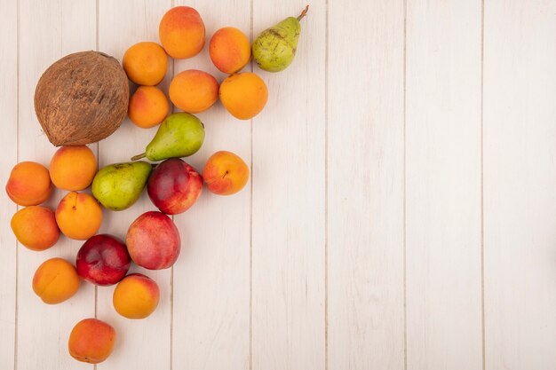 Vista superior del patrón de frutas como coco pera melocotón albaricoque sobre fondo de madera con espacio de copia