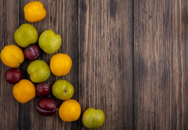 Vista superior del patrón de frutas como pluots verdes sabor pluots rey y nectacots sobre fondo de madera con espacio de copia