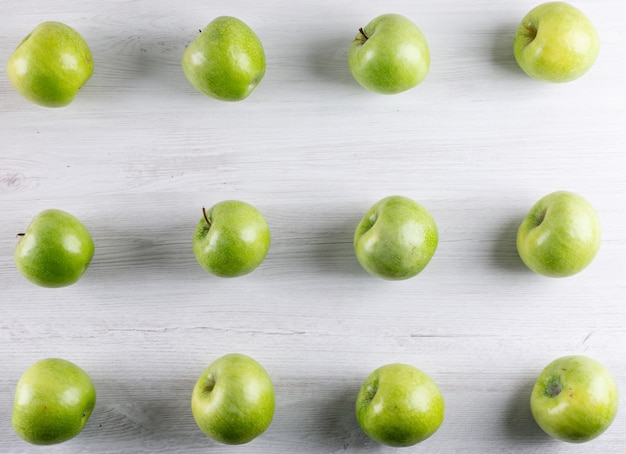 Vista superior del patrón de manzanas verdes en blanco horizontal de madera