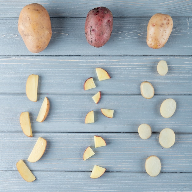 Foto gratuita vista superior del patrón de papas en rodajas y enteras sobre fondo de madera