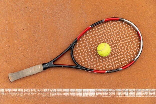 Foto gratuita vista superior pelota de tenis con raqueta en el suelo