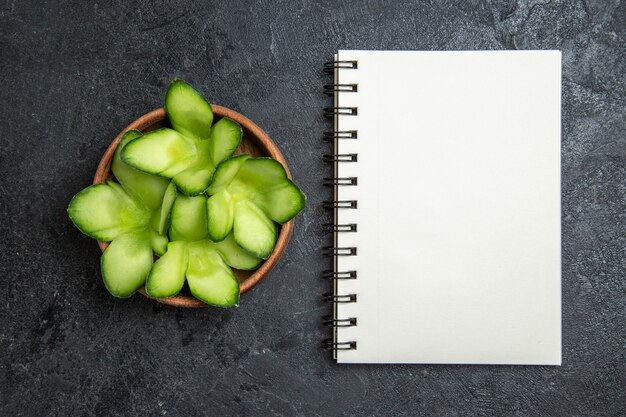 Vista superior de pepinos diseñados en rodajas dentro de la olla sobre fondo gris ensalada de verduras de dieta saludable