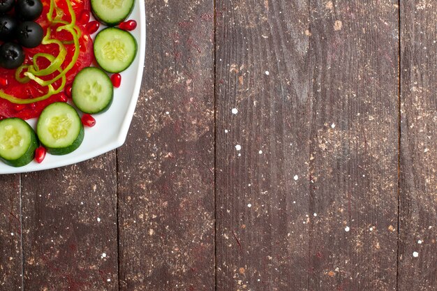 Vista superior de pepinos en rodajas con aceitunas dentro de la placa en el escritorio rústico marrón dieta ensalada vegetal vitamina salud