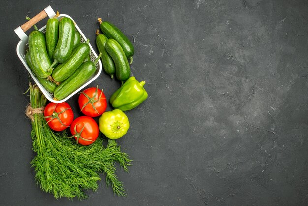 Vista superior de pepinos verdes frescos con verduras y verduras sobre fondo oscuro