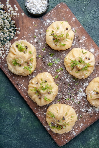 Vista superior pequeñas albóndigas crudas con carne en el interior en la superficie azul oscuro masa de carne plato de cocina pastel cena comida cocinar