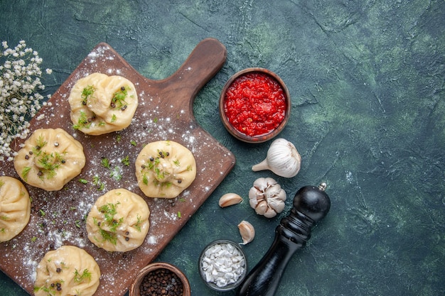 Vista superior pequeñas albóndigas crudas con salsa de tomate sobre fondo azul oscuro cena plato de masa de carne pastel comida cocina cocina