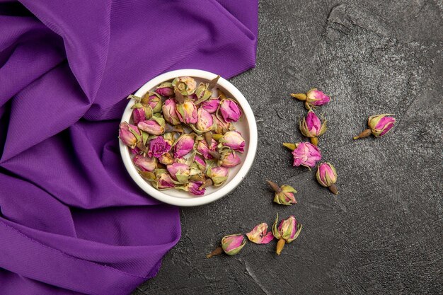 Vista superior de pequeñas flores púrpuras con tejido púrpura sobre gris