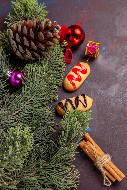 Vista superior de pequeñas galletas con árbol y conos en mesa negra