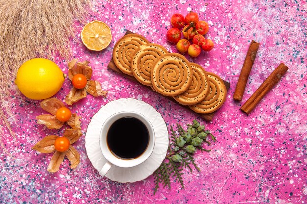 Vista superior de pequeñas galletas deliciosas con té de limón y canela en la superficie de color rosa claro