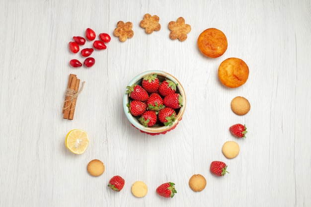 Vista superior pequeñas galletas con frutas frescas en el escritorio blanco