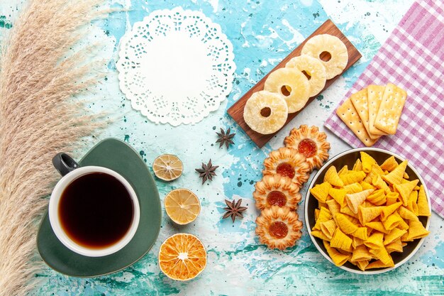 Vista superior pequeñas patatas fritas picantes con galletas de té, anillos de piña secos y galletas en chips de superficie azul color de snack calorías crujientes