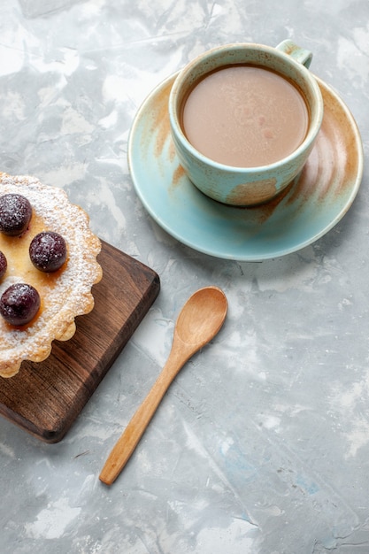 Foto gratuita vista superior pequeño pastel delicioso con azúcar en polvo y cerezas junto con café con leche en el escritorio ligero pastel de frutas galleta dulce foto color