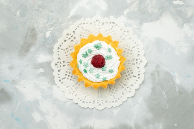 Vista superior pequeño pastel delicioso con crema en la mesa de luz masa dulce