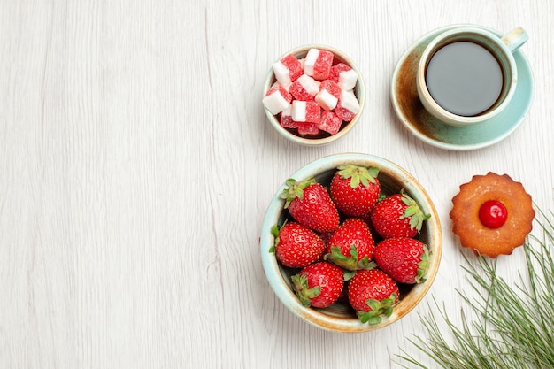 Foto gratuita vista superior del pequeño pastel con frutas y una taza de té en el escritorio blanco