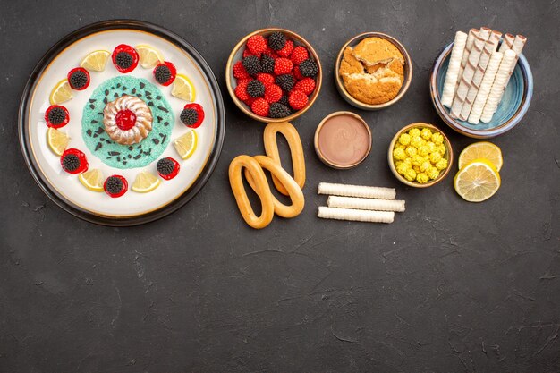 Vista superior pequeño pastel de galletas con rodajas de limón y caramelos en el fondo oscuro pastel galleta dulce fruta cítrica galleta