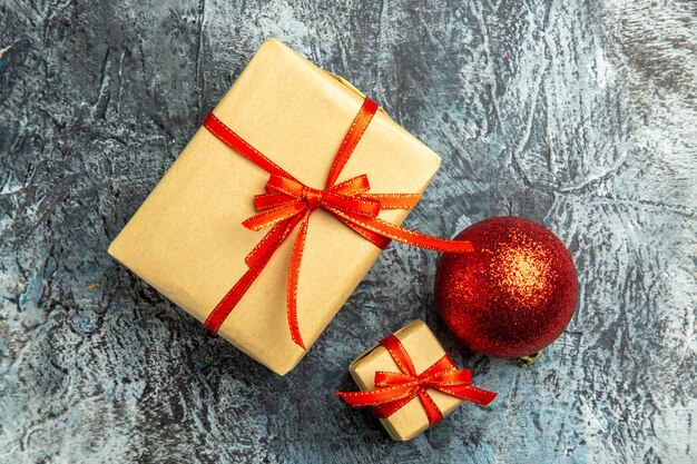 Vista superior pequeño regalo atado con cinta roja bola de árbol de Navidad roja sobre superficie oscura