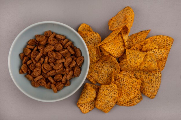 Vista superior de pequeños bizcochos de centeno en un recipiente con sabrosas patatas fritas aislado