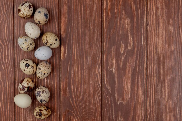 Vista superior de pequeños huevos de codorniz frescos aislados en un fondo de madera con espacio de copia