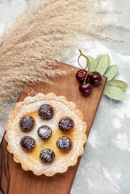 Vista superior de pequeños pasteles con crema de frutas de azúcar en polvo en la mesa de luz pastel crema fruta dulce