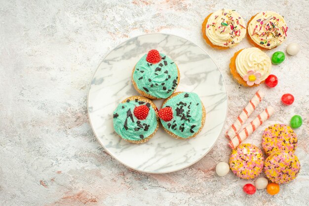 Vista superior de pequeños pasteles cremosos con galletas de galleta en la superficie blanca pastel de galletas de postre crema