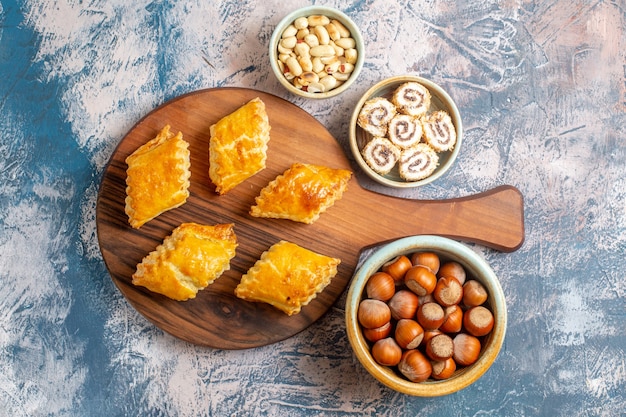 Vista superior de pequeños pasteles dulces con nueces sobre superficie azul