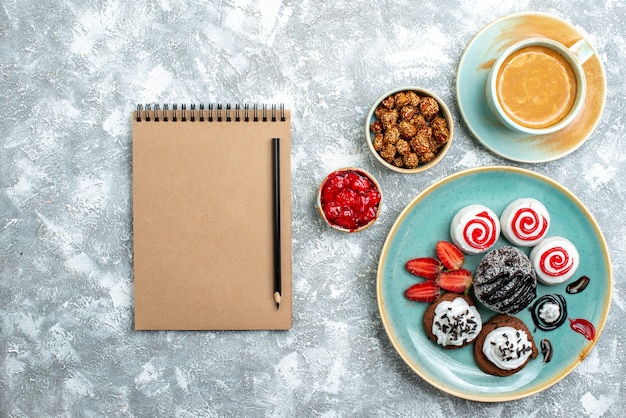 Foto gratuita vista superior de pequeños pasteles dulces con taza de café sobre fondo blanco pastel de tarta galleta dulce galleta de azúcar