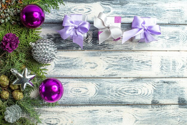 Vista superior pequeños regalos árbol de navidad juguetes ramas de abeto sobre fondo de madera espacio libre