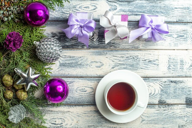 Vista superior pequeños regalos árbol de navidad juguetes ramas de abeto una taza de té en la superficie de madera