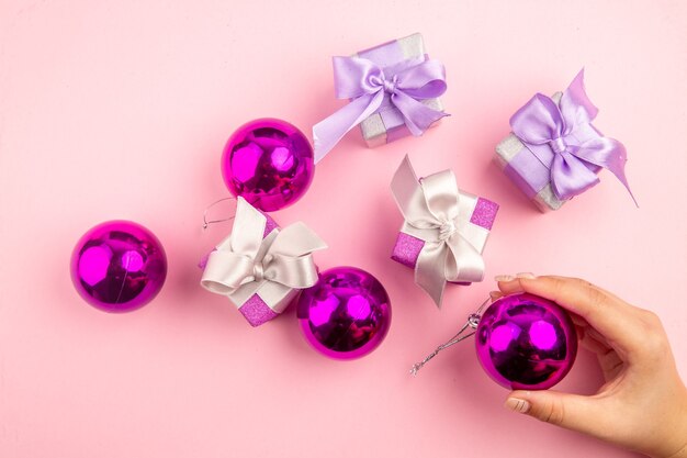 Vista superior de pequeños regalos con juguetes de árbol de Navidad en superficie rosa
