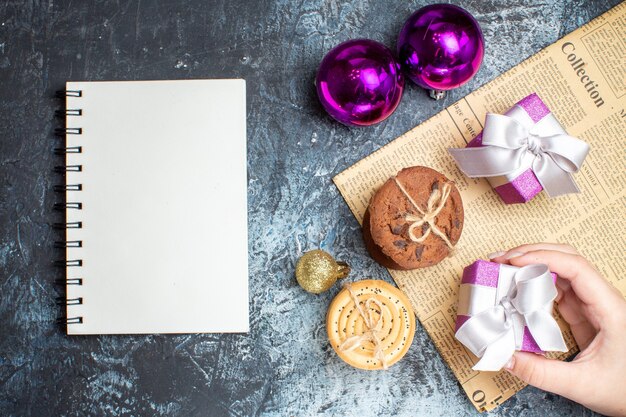 Vista superior de pequeños regalos de Navidad con galletas y juguetes sobre fondo claro-oscuro