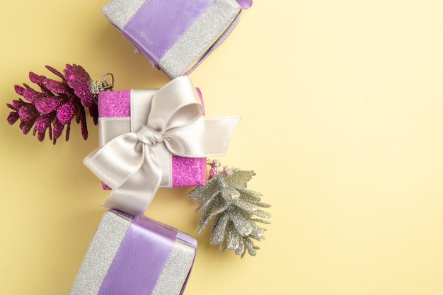 Foto gratuita vista superior de pequeños regalos de navidad en superficie de color amarillo claro
