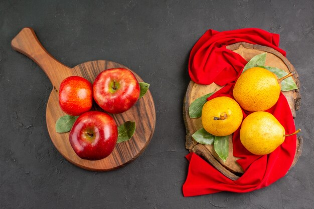 Vista superior peras dulces frescas con manzanas en la mesa gris oscuro árbol meloso fresco maduro rojo