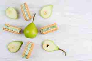 Foto gratuita una vista superior de peras verdes frescas en rodajas y enteras con galletas de frutas en el escritorio blanco color de fruta
