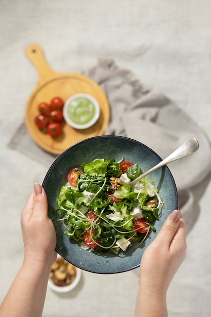 Vista superior de la persona que sostiene un plato de ensalada y un tenedor