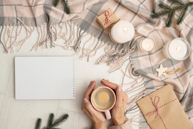 Vista superior de la persona que sostiene la taza con manta y velas