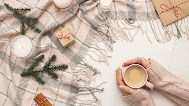 Vista superior de la persona que sostiene la taza con velas y manta